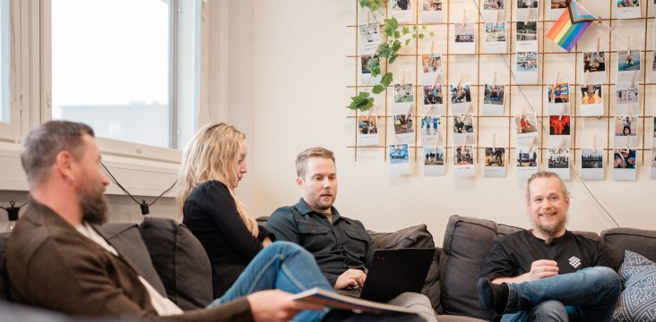 Rento keskustelu oleskelutilassa, yhdellä henkilöllä kädessään painettu esite – 5 asiaa mitä hakukoneoptimointi ei ole