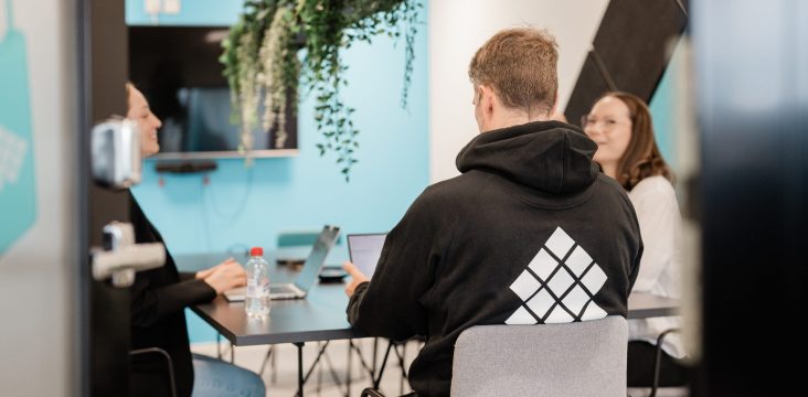 Kolme ihmistä palaveripöydän ääressä huoneessa, jossa on turkoosi seinä ja riippukasveja – Digital Heart Capital kiihdyttää startupeja digisydämellä