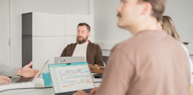 A meeting in a white room with laptops and a turquoise mug on the table – 31 | Investing in happy companies with Timo Ketonen