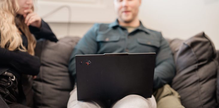 A long-haired colleague sits next to a person using a laptop – Customer-centric development: 5 tips for creating an engaging website