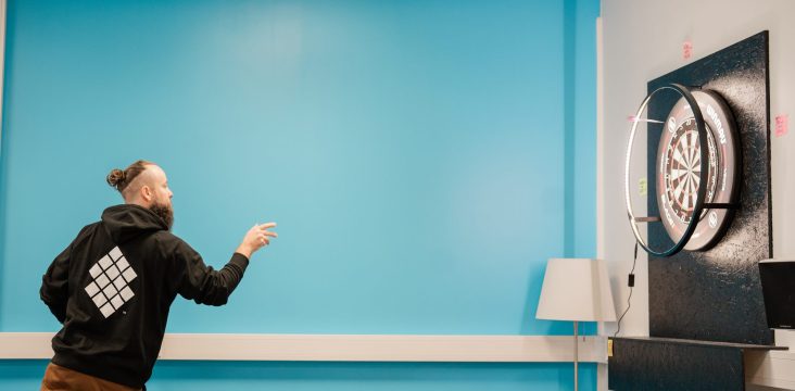 Henkilö heittää tikkaa huoneessa, jossa on turkoosi seinä ja musta tikkataululevy – Windows 8 tulee. Mutta kannattaako sinun vaivautua?