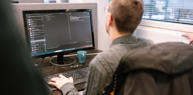 Työpiste, jolla on näyttö, näppäimistö ja turkoosi muki – Case: Kauppakeskus Goodman