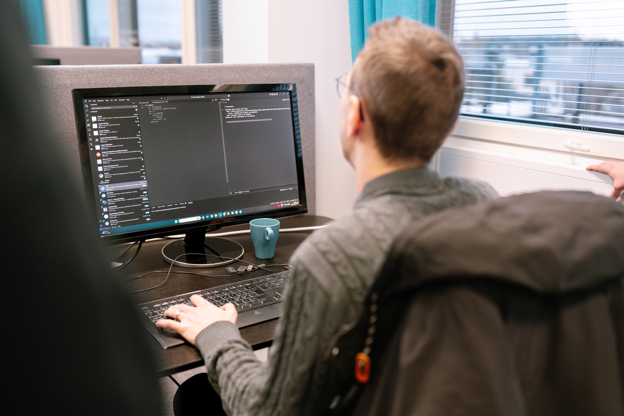Työpiste, jolla on näyttö, näppäimistö ja turkoosi muki – Case: Kauppakeskus Goodman