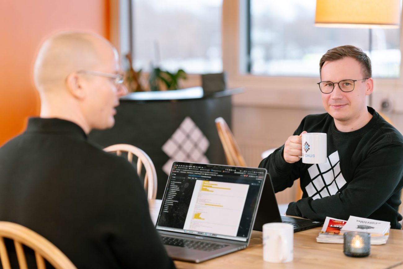 Two Sofokus colleagues in conversation over coffee at a laptop