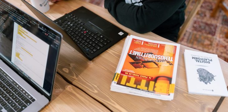 Kaksi läppäriä, lehtiä ja kirja puupöydällä ylhäältä kuvattuna – Mitä on responsiivinen design?
