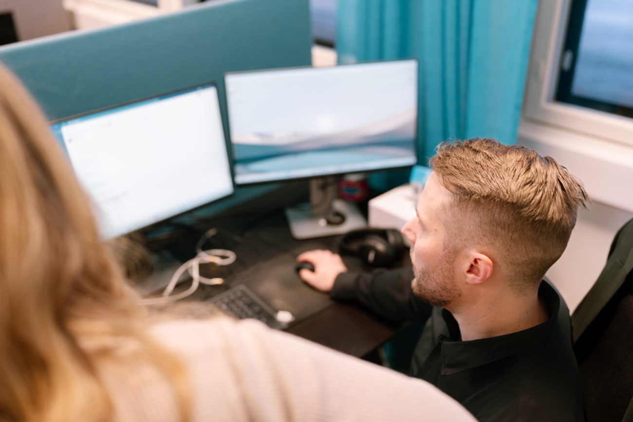 A Sofokus developer working at dual monitors with a colleague