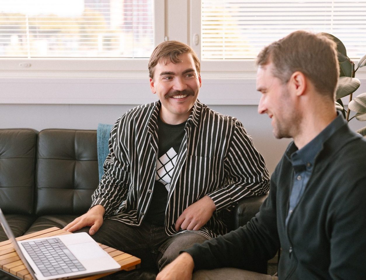 A relaxed conversation on a sofa by a bright window with blinds – Platform economy