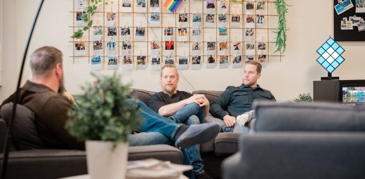 Etualalla parrakas henkilö juttelee kahden sohvalla istuvan kollegan kanssa – Mitä tarkoittaa koottava verkkokauppa?