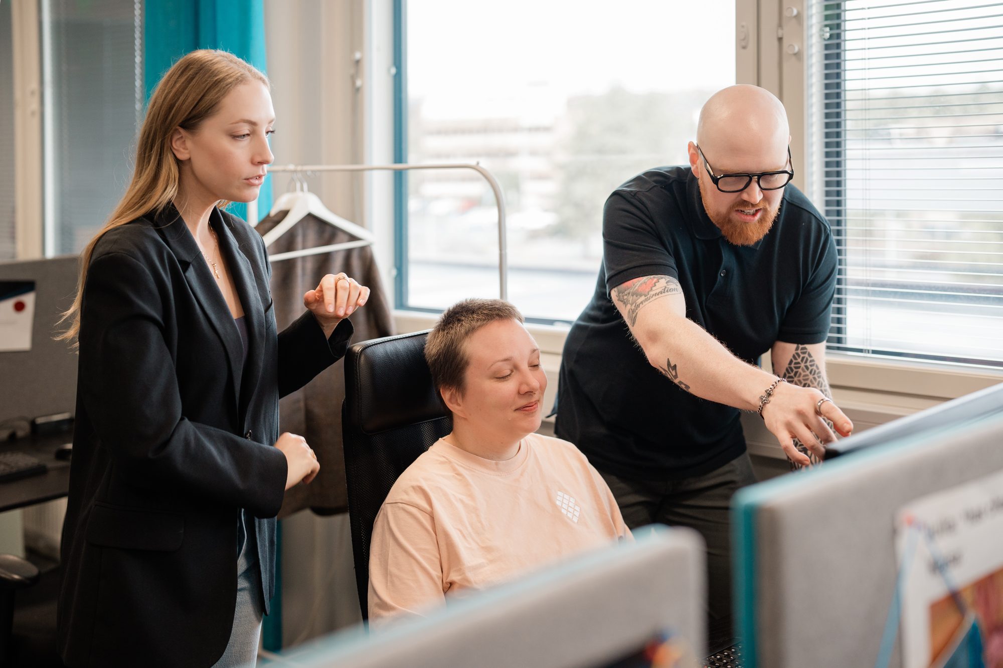 Helping a colleague at their desk in a bright open office – Adaptable Business
