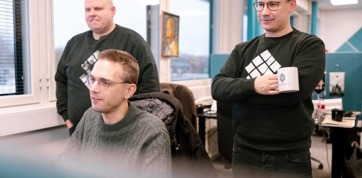 Kolme ihmistä seuraa näyttöä avokonttorissa, kaksi seisoo ja yksi istuu – Sofokus kasvuloikkasi ostamalla Punos Mobilen liiketoiminnan