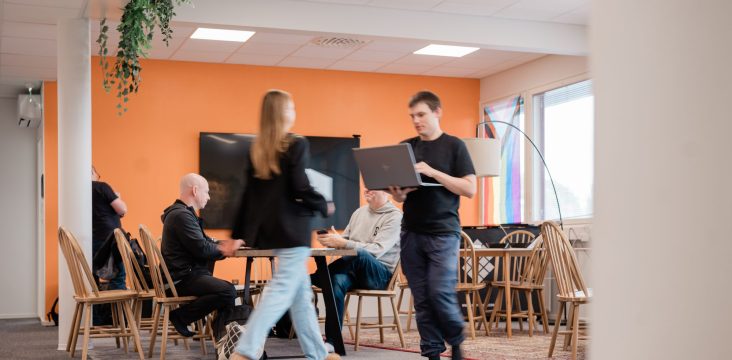 Liikkeen vuoksi epätarkka henkilö kulkee huoneen poikki, taustalla kollegat työskentelevät – 8 tapaa, joilla epämääräinen yritysportaali kosiskelee sinua