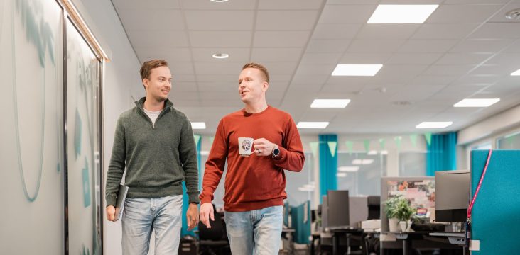 Two smiling colleagues on their way through an open-plan office – Waltti Solutions
